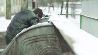 Dilenci evsiz bir serseri çöp tenekesinde yiyecek arıyor. Kyiv. Ukrayna