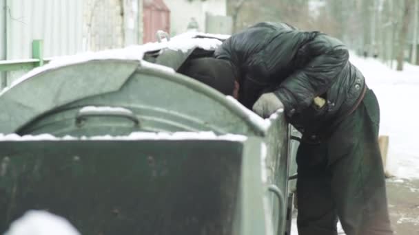 A beggar homeless man tramp is looking for food in a trash can. Kyiv. Ukraine — Stock Video