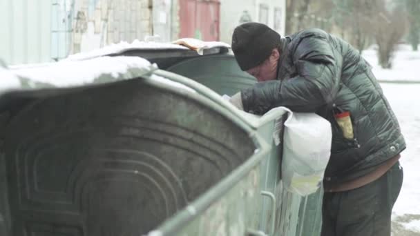 Ein Bettler, der obdachlos ist, sucht in einem Mülleimer nach Essen. Kiew. Ukraine — Stockvideo