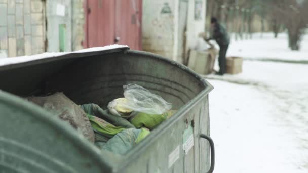 Un vagabundo mendigo sin hogar está buscando comida en un cubo de basura. Kiev. Ucrania — Vídeos de Stock