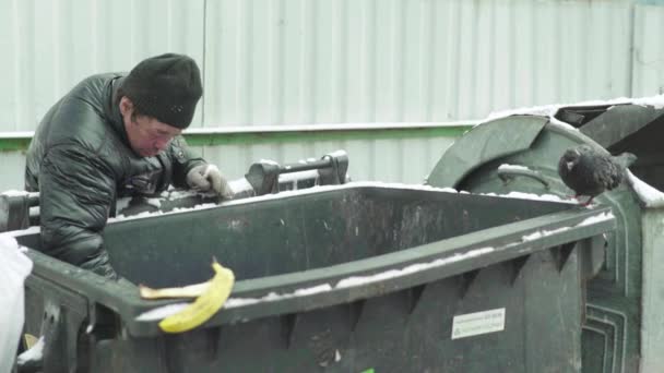 Ein Bettler, der obdachlos ist, sucht in einem Mülleimer nach Essen. Kiew. Ukraine — Stockvideo