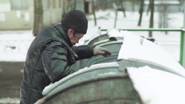 Un vagabundo mendigo sin hogar está buscando comida en un cubo de basura. Kiev. Ucrania — Vídeos de Stock