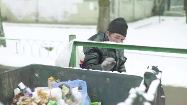 Ein Bettler, der obdachlos ist, sucht in einem Mülleimer nach Essen. Kiew. Ukraine — Stockvideo