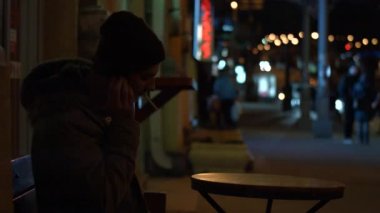 Adam gece sokakta cep telefonuyla konuşuyor.