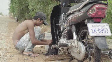 Adam motosikletini yıkıyor. Phnom Penh, Kamboçya, Asya