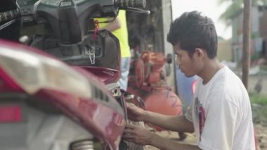 Adam motosikletini yıkıyor. Phnom Penh, Kamboçya, Asya