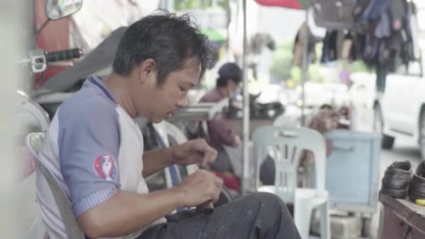 A man repairs shoes on a street of Phnom Penh, Cambodia, Asia — Stock Video