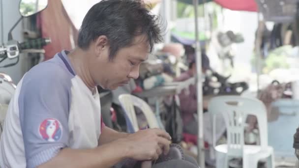 캄보디아의 프놈펜 거리에서 신발을 수리하고 있는 남자 — 비디오