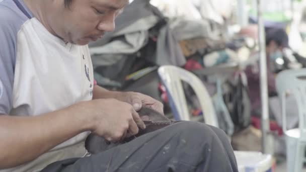 Een man repareert schoenen in een straat in Phnom Penh, Cambodja, Azië — Stockvideo