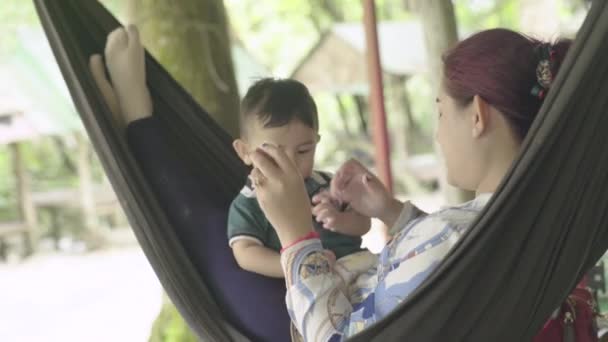 Žena s dítětem odpočívá v houpací síti. Dítě jí tropické ovoce. Sihanoukville, Kambodža, Asie. — Stock video