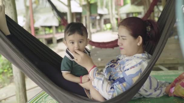 Eine Frau ruht mit ihrem Baby in einer Hängematte. Kind isst tropische Früchte. Sihanoukville, Kambodscha, Asien. — Stockvideo