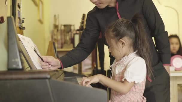 Музична школа в Пномпені, Камбоджа, Азія. Вчителька вчить дівчину грати на піаніно. — стокове відео