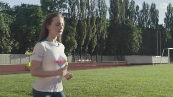 En atletisk ung flicka springer på stadion. Långsamma rörelser — Stockvideo