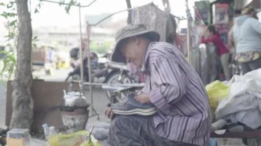 Kamboçya 'da günlük yaşam. Asya. Bir adam sokakta ayakkabı temizliyor. Ayakkabı temizleyici.