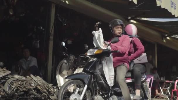 Повседневная жизнь в Камбодже. Азия. Мужчина с женой на мотоцикле . — стоковое видео
