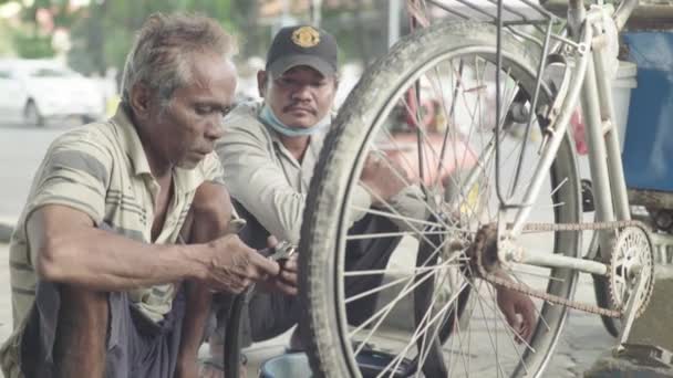 La vida cotidiana en Camboya. Asia. Un hombre está reparando una rueda de bicicleta — Vídeos de Stock