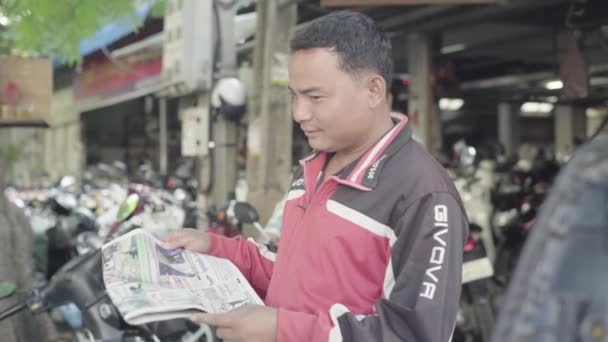 Alltag in Kambodscha. Asien. Ein Mann liest in einer Straße von Phnom Penh eine Zeitung — Stockvideo