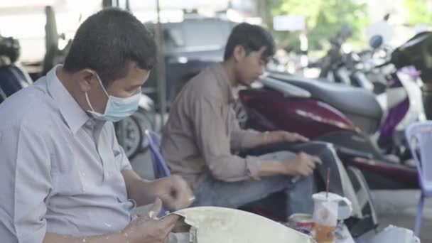 A mindennapi élet Kambodzsában. Ázsiában. Motorkerékpár javító műhely az utcán Phnom Penh — Stock videók