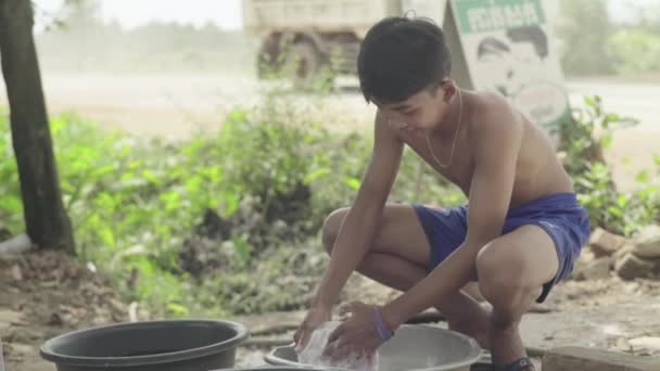 La vida cotidiana en Camboya. Asia. Un chico lava platos cerca de la carretera — Vídeo de stock