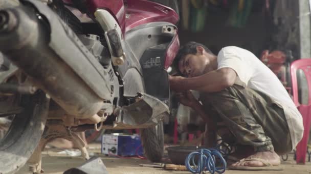 Щоденне життя в Камбоджі. Азія. Чоловік ремонтує велосипед. Ремонт мотоциклів — стокове відео