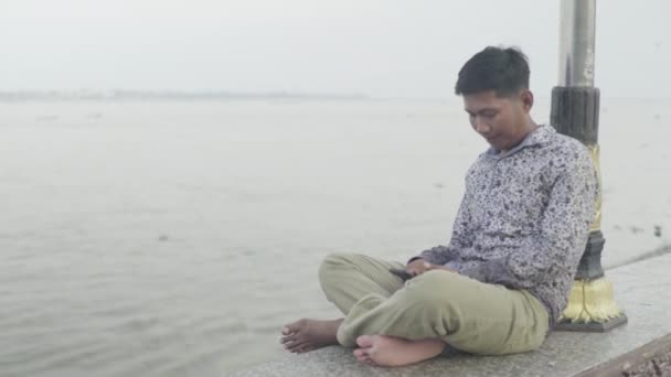 Повседневная жизнь в Камбодже. Азия. Человек на берегу реки Меконг в Пномпене — стоковое видео