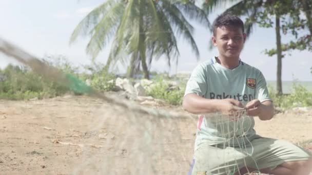 A male fisherman is fixing a fishing net on the beach of Sihanoukville. Cambodia. Asia — Stock Video