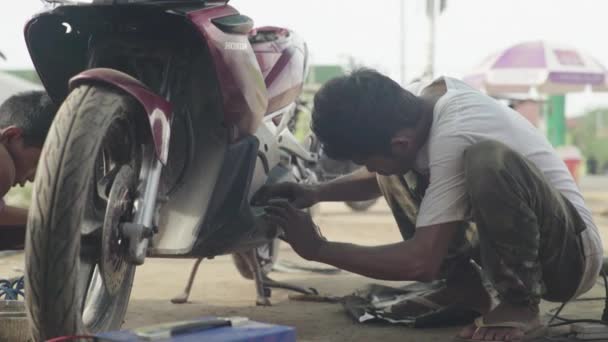 Alltag in Kambodscha. Asien. Der Typ repariert ein Motorrad — Stockvideo