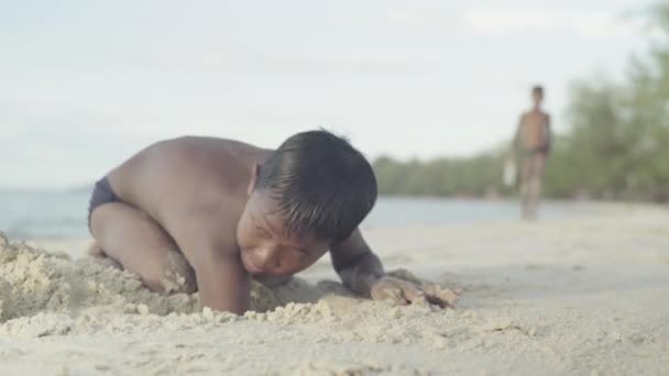 Um menino cava na areia em uma praia em Sihanoukville, Camboja — Vídeo de Stock