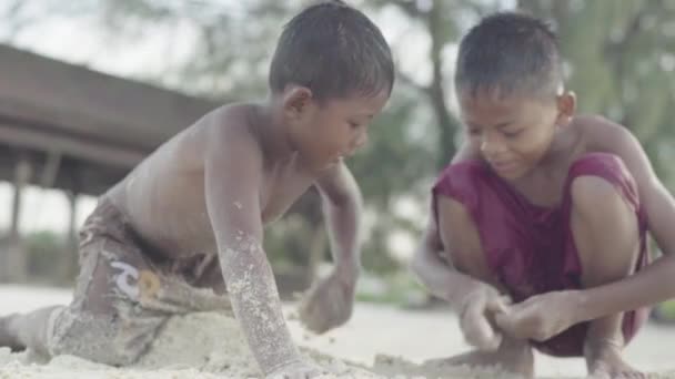 Two boys rummaging in the sand on a beach in Sihanoukville, Cambodia. Asia. — Stock Video