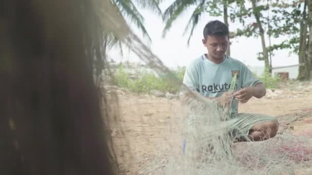 Ένας αρσενικός ψαράς φτιάχνει ένα δίχτυ ψαρέματος στην παραλία της Σιχανούκβιλ. Καμπότζη. Ασία — Αρχείο Βίντεο