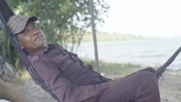 La vie quotidienne au Cambodge. L'Asie. Un homme se repose couché dans un hamac près de la mer — Video