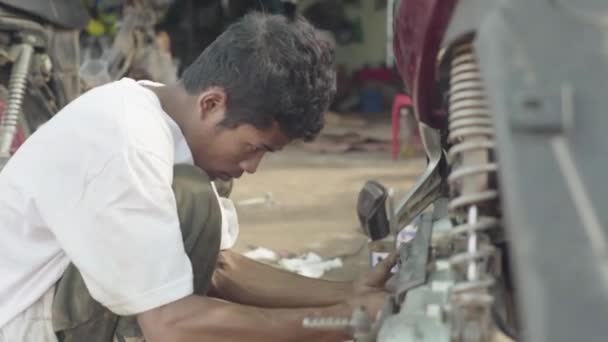 Det dagliga livet i Kambodja. Asien. Killen reparerar en motorcykel — Stockvideo