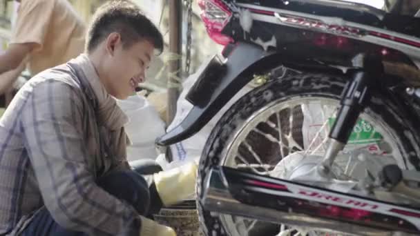 Det dagliga livet i Kambodja. Asien. Killen tvättar en motorcykel — Stockvideo