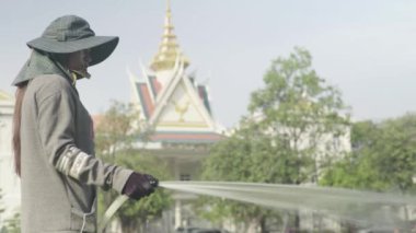 Kamboçya 'da gerçek insan hayatı: bir kadın çim hortumlar. Phnom Penh. Asya