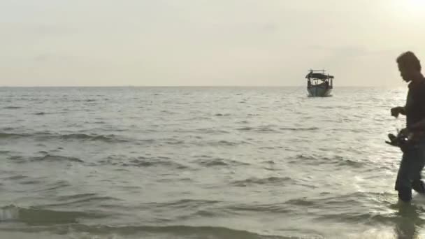 Пляж у Сіануквіллі, Камбоджа, Азія. Чоловік йде по воді вздовж берега. — стокове відео