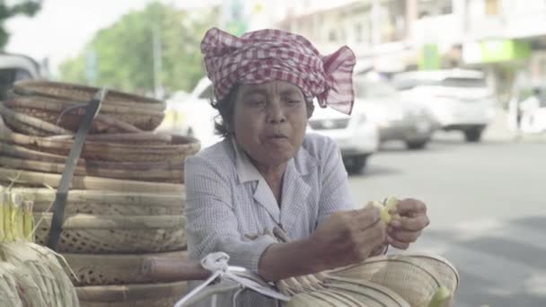 Μια ηλικιωμένη γυναίκα τρώει μια μπανάνα σε ένα δρόμο της Πνομ Πενχ, Καμπότζη, Ασία — Αρχείο Βίντεο