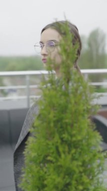 Dikey video. Gözlüklü ve gri takım elbiseli güzel bir kız. Yavaş çekim