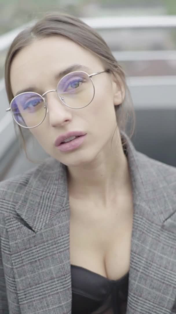 Vídeo vertical. Hermosa chica en gafas y un traje gris. Movimiento lento — Vídeos de Stock