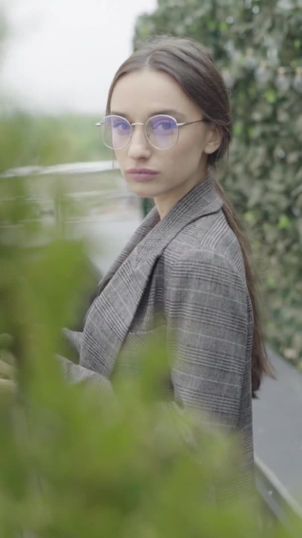 Vertical video. Beautiful girl in glasses and a gray suit. Slow motion — Stock Video
