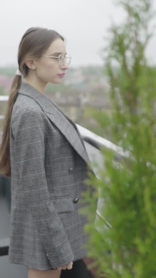 Vídeo vertical. Hermosa chica en gafas y un traje gris. Movimiento lento — Vídeos de Stock