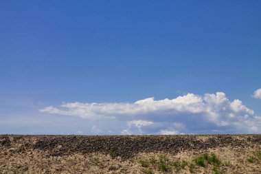 Beyaz bulutlu mavi gökyüzü. Kayalık arazi.