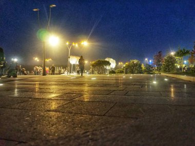Güzel ışıklandırmalı ve insanların yürüdüğü bir akşam meydanı..