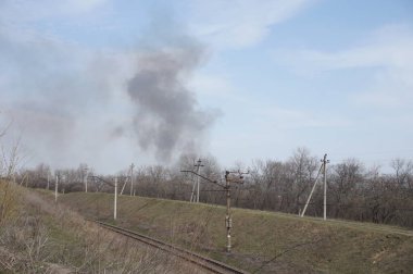 Demiryolunun üstündeki gökyüzünde siyah duman.