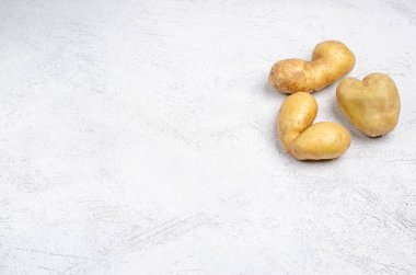 Despicable potatoes of different shapes on a gray background, copy space