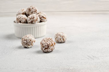 Enerji dolu hurmalar, fındıklar, yulaflar, üzerine hindistan cevizi tozu serpiştirilmiş beyaz bir tabakta yakın plan fotokopi arkaplanlı.