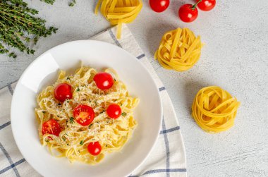 Domatesli ev yapımı tagliatelle makarna, kekik, beyaz bir tabakta parmesan peyniri. Düz yatıyordu. Düzgün beslenme, diyet. Yukarıdan görüntüle