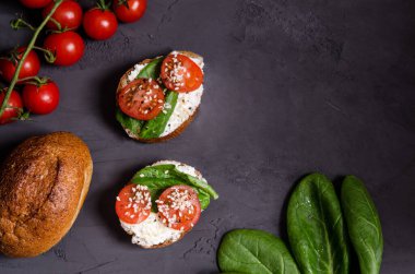 Krem peynirli ev yapımı sandviçler, domatesler, Yunan dürümündeki ıspanak koyu arkaplanda maya yok, fotokopi alanı. Düz yatıyordu. Sağlıklı beslenme, sağlıklı atıştırma. Yukarıdan görüntüle.
