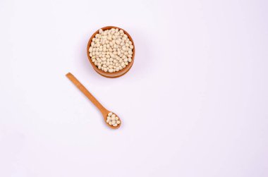 Tahta kaşıkta vejetaryenler için kuru fasulye ve beyaz arka planda bowling, fotokopi alanı, mesaj için yer. Yüksek miktarda protein ve karbonhidrat içeren sağlıklı yiyecekler. Yukarıdan görüntüle.