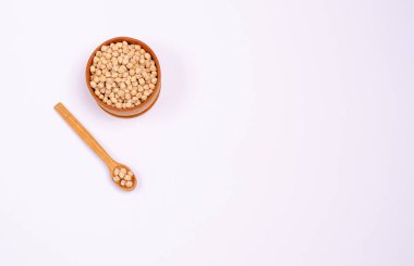 Tahta bir kaşıkta vejetaryenler için kuru nohut ve beyaz bir arka planda bowling, kopya alanı, mesaj için yer. Yüksek miktarda protein ve karbonhidrat içeren sağlıklı yiyecekler. Yukarıdan bak. Yatay yönelim.