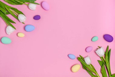 Renkli Paskalya yumurtaları ve pembe arka planda bir buket beyaz lale, fotokopi alanı, düz yatak. Mesaj için yer. Tatil konsepti, bahar. Yukarıdan görüntüle.